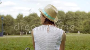 年轻的女学生坐在大学校园的草地上放松。 公共公园的游客白日梦